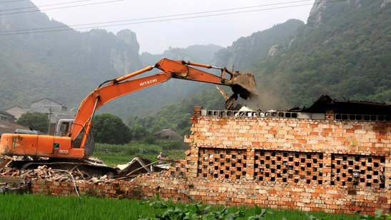 执法人员调来大型履带式挖土机对铸件企业的违法建筑进行依法强制拆除